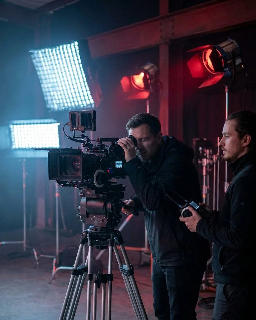 Cinematographer and focus puller with a digital cinema camera on a film set with lights and haze